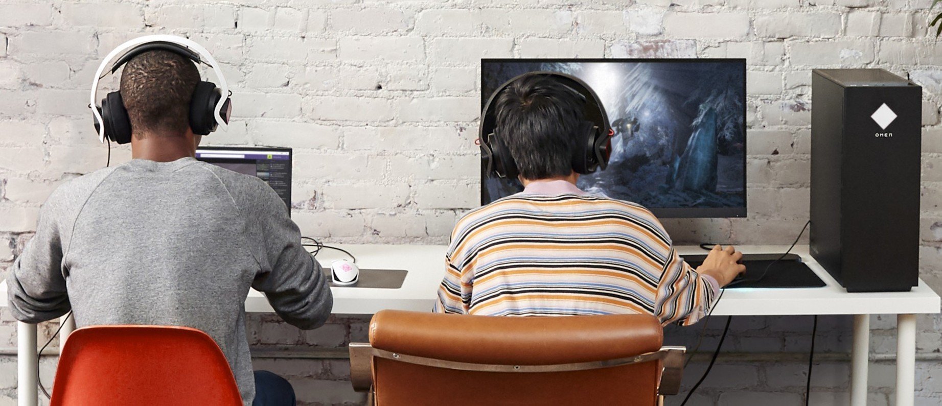 Two players enjoying video games on HP gaming PCs in a modern living room with white brick walls and minimalist decor
